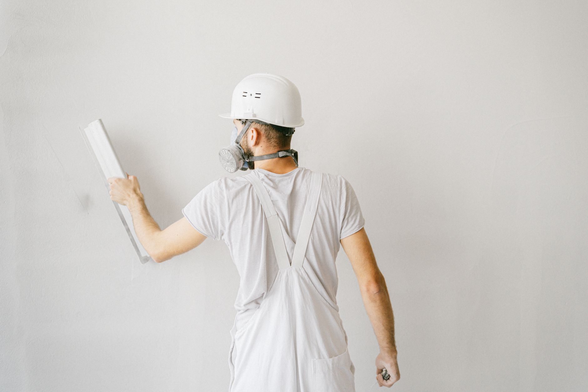 Trabalhador aplicando gesso em parede branca